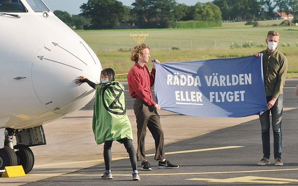 Zdjęcie akcji z rebeliantami trzymającymi baner „Ratujemy świat ALBOlotnictwo”.