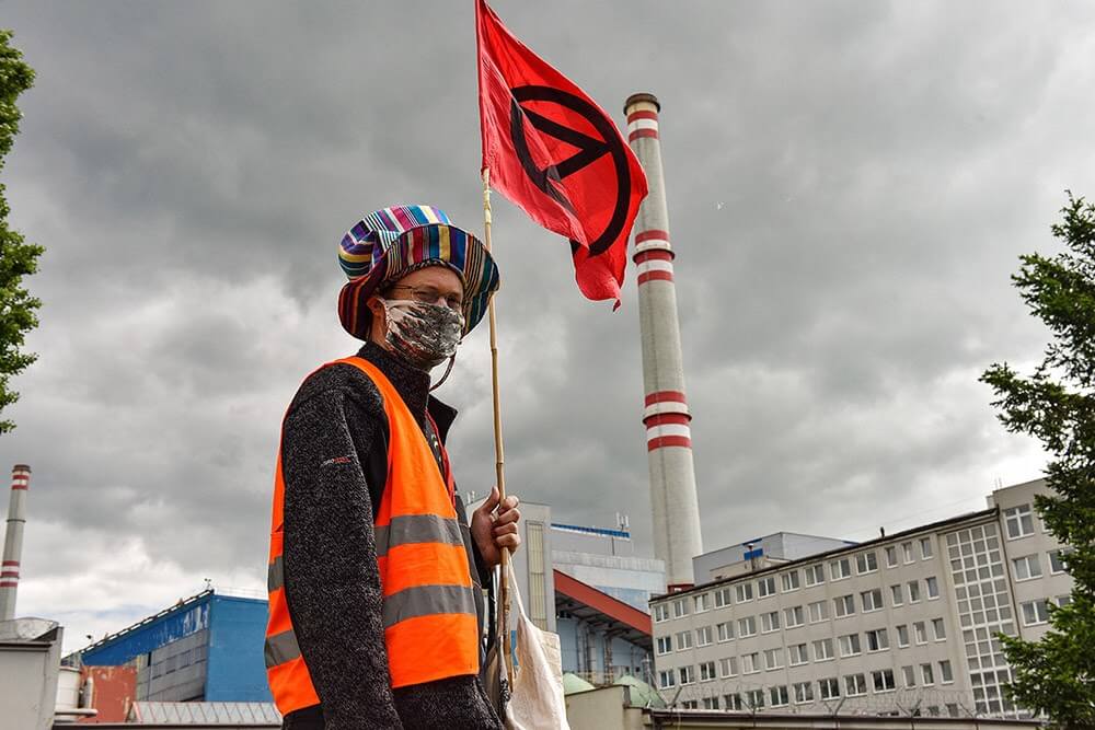 Rebel with an extinction rebellion flag in front of power station