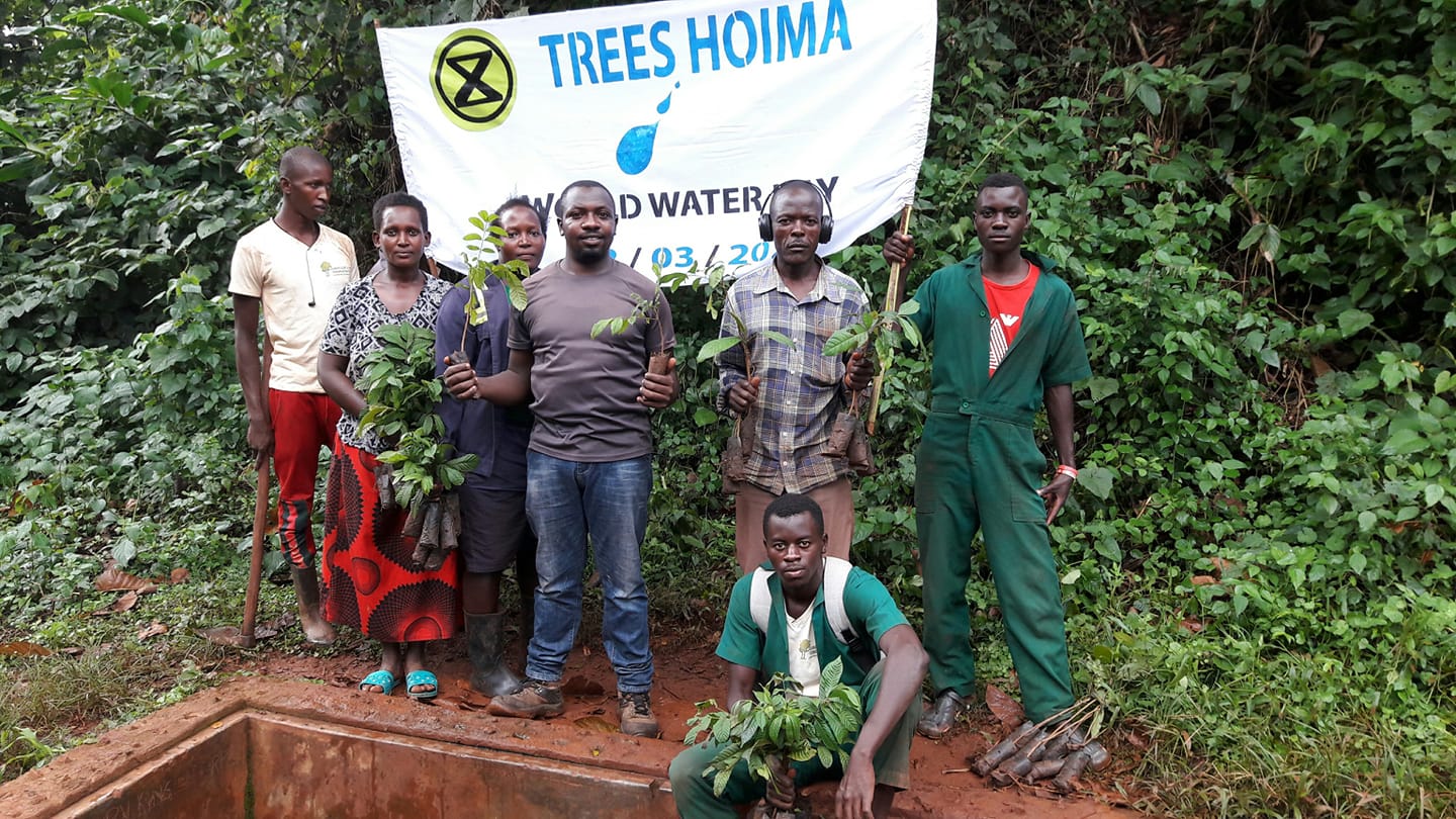 Rebelové z XR Uganda drží sazenice stromků před začátkem sázecíakce.