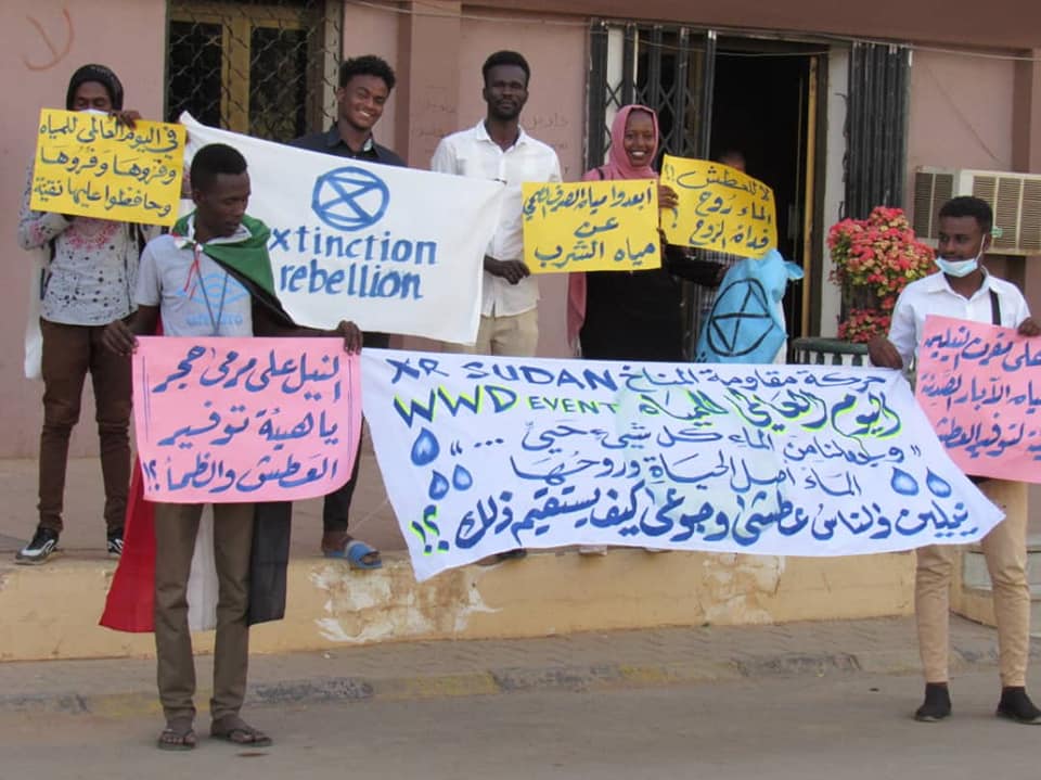 Sudańscy_kie rebelianci_tki obchodzący Światowy Dzień Wody. Na dużymbanerze jest cytat z Koranu: „Stworzyliśmy z wody każdą istotę żywą. Czyżoni w to nie wierzą?!”