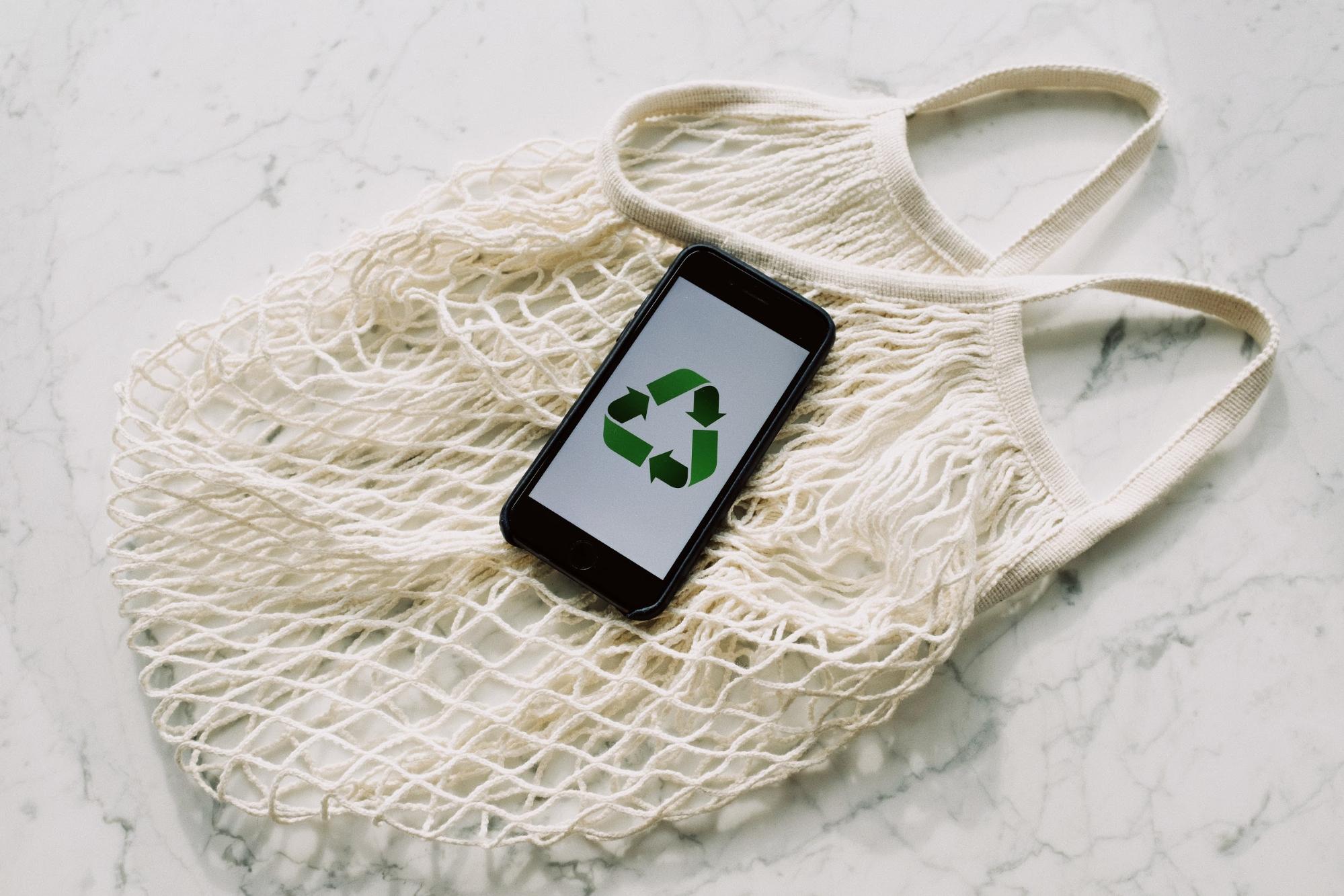 Smartphone mit eingeblendetem Recyclingsymbol