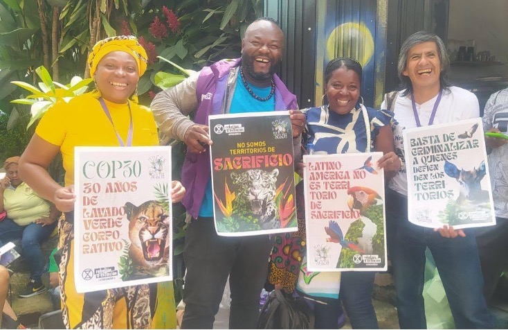 A photo of four people posing together, smiling and holding posters.