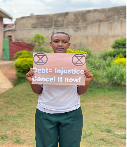 Youth climate advocate holds a "Debt = Injustice — Cancel it now!" placard during the Cancel the Debt, Heal the Planet action in Kigali.