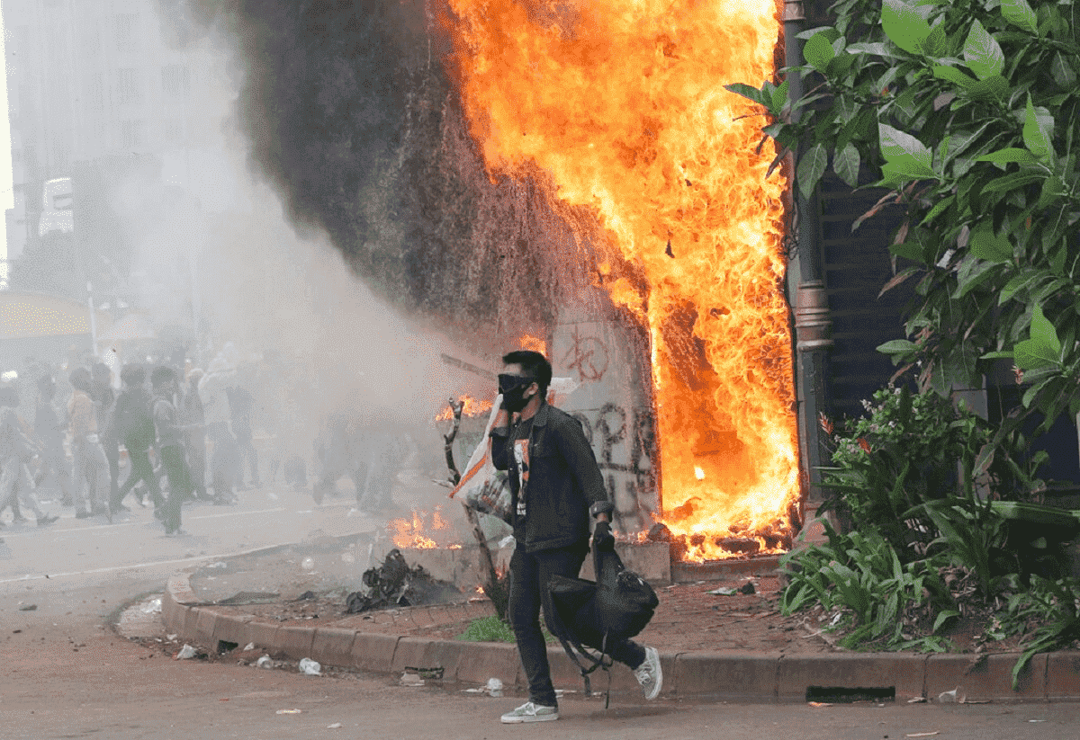 Demonstrant vor einem brennendenGebäude