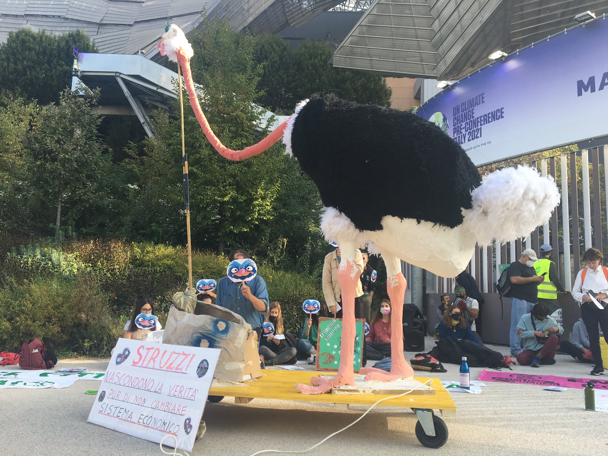 A giant model of an ostrich stands with kneeling rebels outside the Milan Convention Centre
