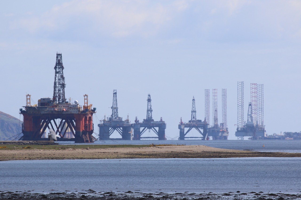 Picture looking out to sea from the Scottish coast - the horizon is dominated by half a dozen oil rigs and related structures.