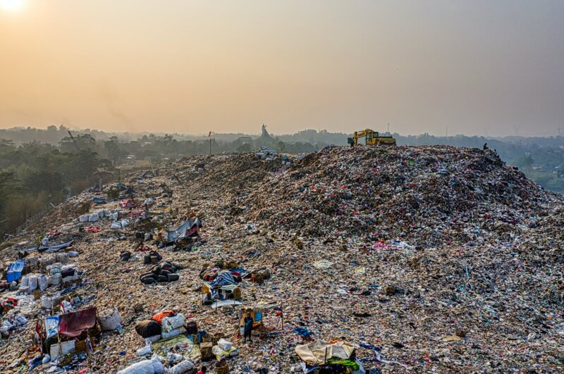 Image shows a massive landfill site that dwarfs surrounding trees.