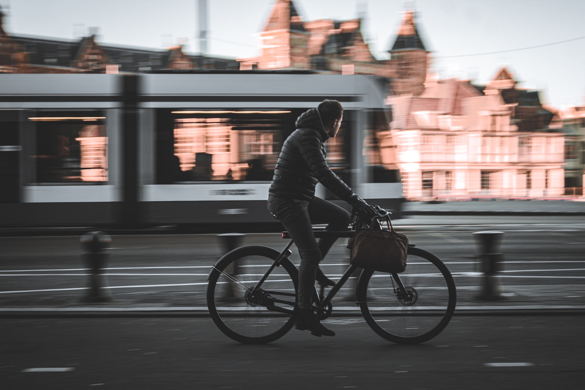 Side on photo of man cycling in European city, tram in background